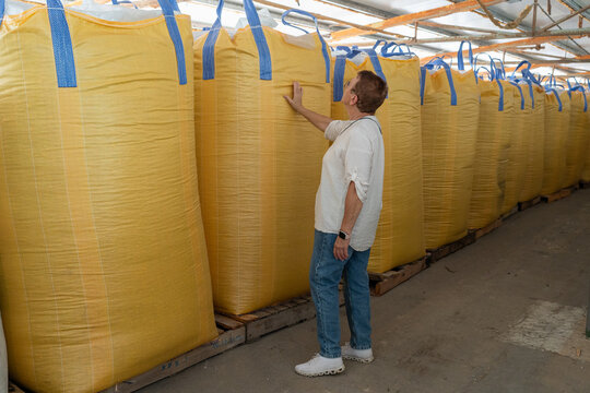 Senior Woman Inspecting Large Yellow Bags in Warehouse During Daylight