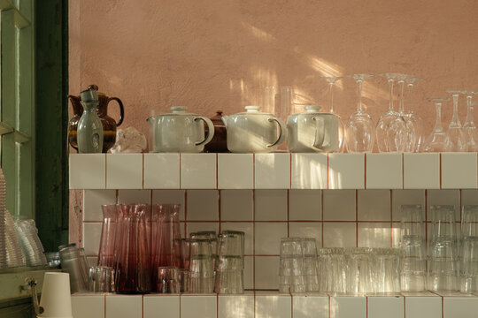 Glassware and ceramic teapots on a shelf in a cozy cafe setting