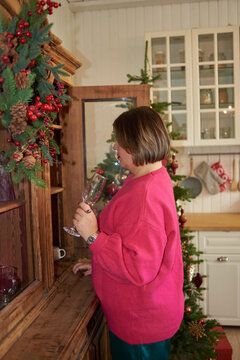 Woman pulls a glass from kitchen cupboard