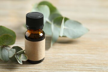 Eucalyptus essential oil in a glass bottle with green eucalyptus leaves on a wooden background. Aromatherapy concept. Spa. Natural organic ingredients for cosmetics and body care.