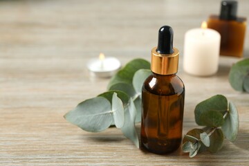Eucalyptus essential oil in a glass bottle with green eucalyptus leaves on a wooden background....