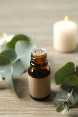 Eucalyptus essential oil in a glass bottle with green eucalyptus leaves on a wooden background. Aromatherapy concept. Spa. Natural organic ingredients for cosmetics and body care.