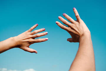 Hand manicure with colorful nails over blue sky