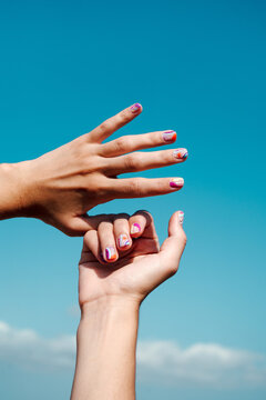 Hand manicure with colorful nails over blue sky
