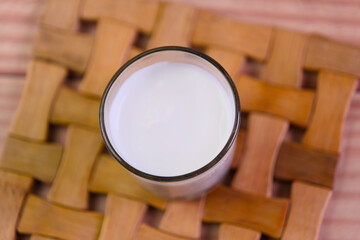 A glass of milk is sitting on a wooden coaster