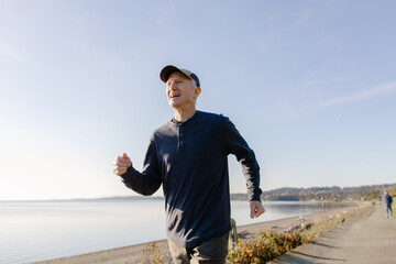 Senior Man Jogging Along a Scenic Lakeside Pathway