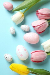 Easter decor concept. Top view photo of colorful eggs with tulip flowers on color background
