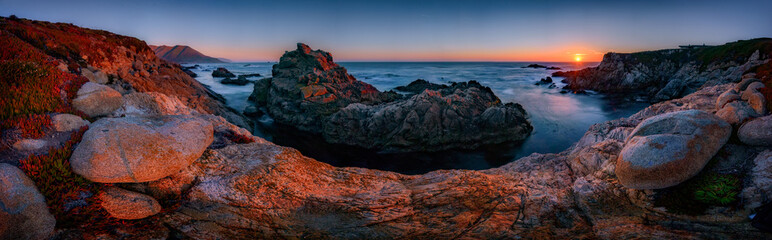 Big Sur Pinnacle Rock panorama at sunset.  Sun on distant Pacific Coast horizon.  
