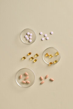 Assorted Pills and Capsules on Beige Background in Petri Dishes