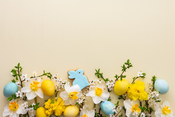 Festive background with spring flowers and naturally colored eggs and Easter bunnies, white daffodils and cherry blossom branches on a yellow pastel background