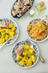 Delicious hearty fish dinners, boiled potatoes with pickled herring, sauerkraut with onions and olive oil, top view