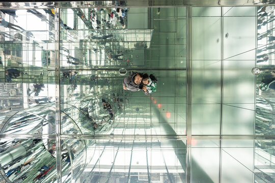 Father and son taking selfie reflecting in glass ceiling in summit