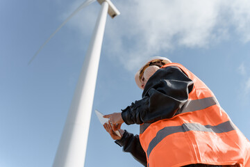 Wind turbine technician using digital tablet working in a wind farm