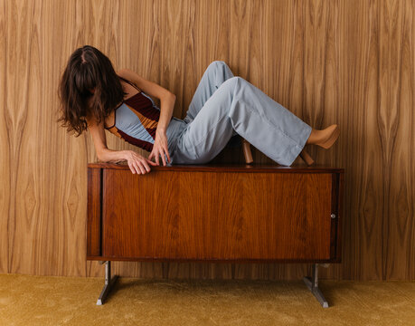 Young Woman Posing Creatively on Vintage Wooden Cabinet