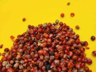 Little red pepper seeds on a yellow background.