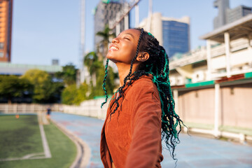 Cheerful hipster woman with eyes closed at sports court