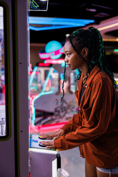 Young hipster woman playing arcade game
