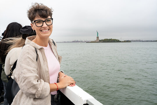 Tourist smiling at the statue of liberty in new york city