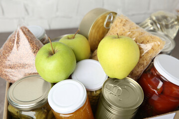 Different products in box on table, closeup. Food donation