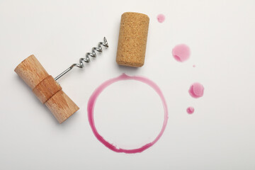 Corkscrew, cork and red wine stains on white background, top view