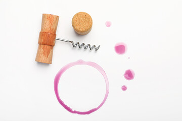 Corkscrew, cork and red wine stains on white background, top view