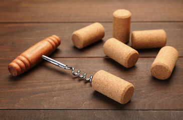 Corkscrew with handle and corks on wooden table