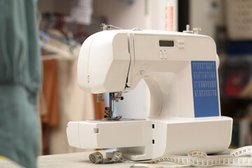 One sewing machine with thread and measuring tape on white table in workshop
