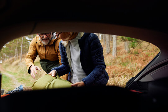 Man and woman take camping things out of the trunk