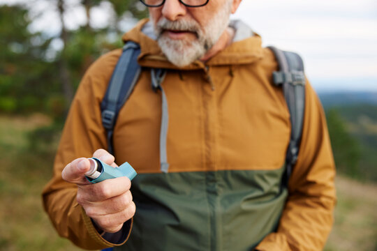 Man holds an inhaler spray on a mountain