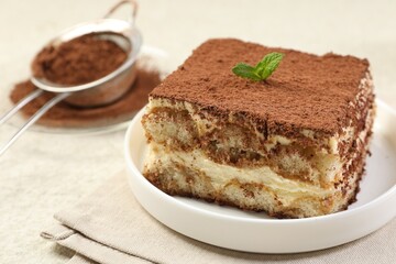 Delicious tiramisu with mint on light table, closeup