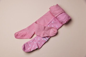 Beautiful pink child's tights on beige background, top view