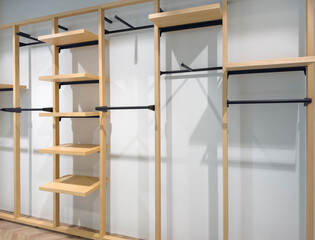 Empty open closet with shelves in clothing store against white wall
