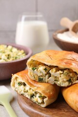 Delicious pirozhki (stuffed pastry pies) and ingredients on grey table, closeup