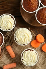 Tasty carrot muffins and fresh vegetables on wooden table, flat lay