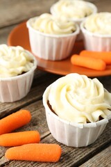Delicious carrot muffins and fresh vegetables on wooden table, closeup