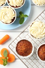 Delicious carrot muffins with fresh vegetables and mint on white wooden table, flat lay