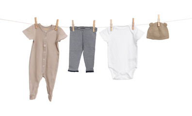 Different baby clothes drying on laundry line against white background