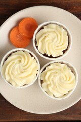 Delicious carrot muffins and fresh vegetable on wooden table, top view