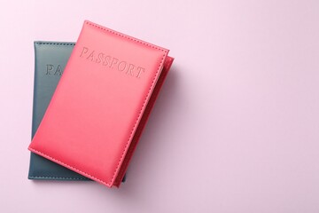 Passports in color covers on pink background, top view. Space for text