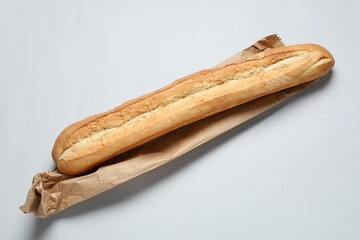 Paper bags and fresh baguette on white background, top view