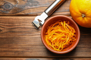 Orange zest, zester tool and fresh fruit on wooden table, flat lay. Space for text