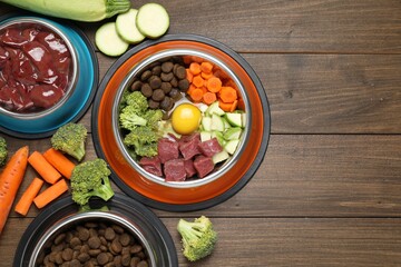 Dry pet food and natural products on wooden table, top view. Space for text