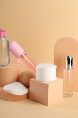 Clean cotton pads and cosmetic products on beige background
