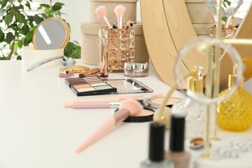 Makeup room. Mirror and different cosmetic products on white dressing table indoors, closeup