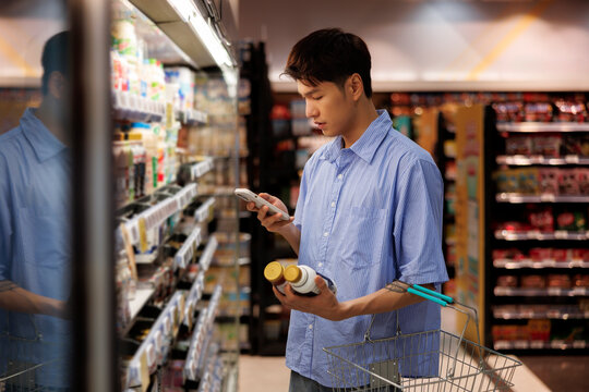 Man holding bottles using smart phone at store