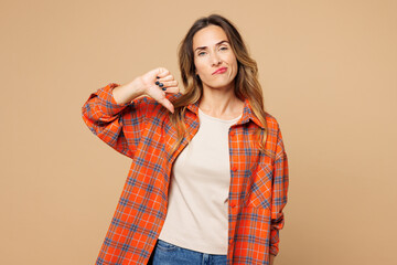 Young sad disappointed dissatisfied woman she wears orange shirt casual clothes showing thumb down...