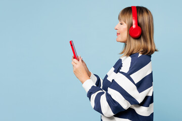 Side view elderly blonde woman 50s years old wear striped sweatshirt casual clothes listen music in...