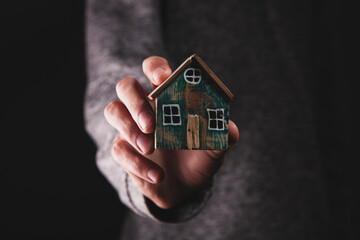 male hands holding small house.