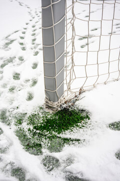 Snow-covered soccer goalpost with footprint