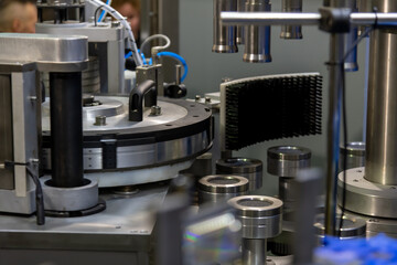 Close-up view of working modern empty metal bottle label applying machine on bottling plant. Soft focus. Copy space. Industrial food and drink technology equipment theme.